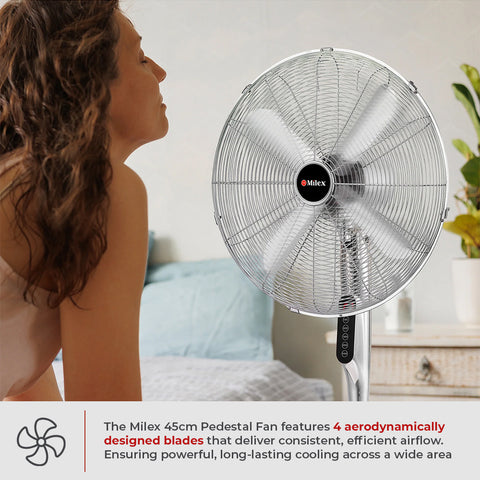 Woman using a Milex pedestal fan in a bedroom setting