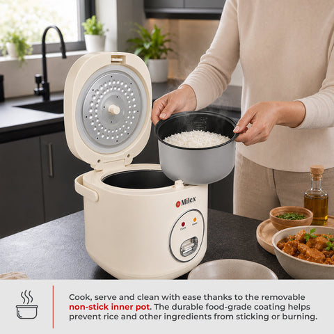 A person in a beige outfit stands at a kitchen counter holding a gray non-stick inner pot filled with white rice next to a Milex rice cooker with its lid open. The scene is set in a modern kitchen with dark cabinets, a sink, and plants in the background, 