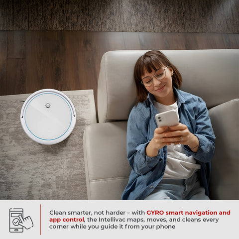 Woman using a smartphone next to a Intellivac 3-in-1 Robot Vacuum Cleaner in a living room.